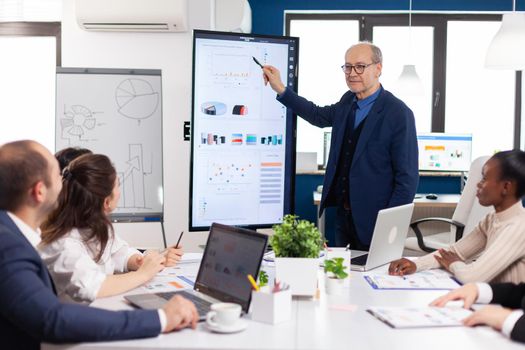 Experienced project leader analysing financial presentation during business conference in brainstorming room using digital devices. Multiethnical businesspeople working in professional startup financial office during conference meeting.