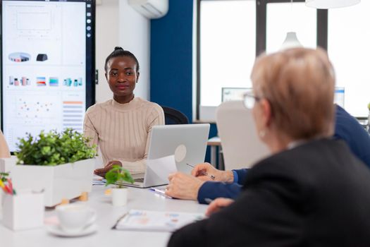 Ethnic executive management planning business plan sitting in boardroom conference meeting. Businesswoman discussing ideas with colleagues about financial strategy for new start up company.