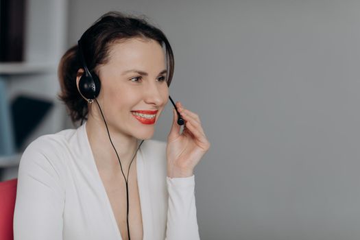 Call-centre lady employee happy of conversation with customer calling by headset. Happy call centre agent talking with their headset in a bright office.