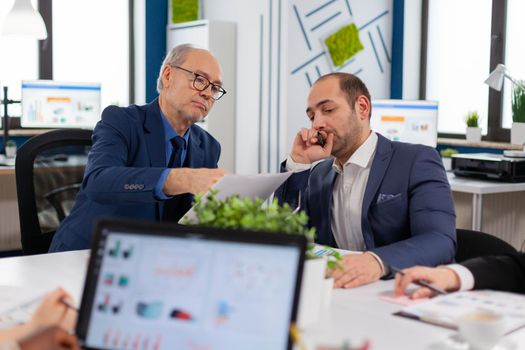 Financial entrepreneurs analysing discussing documents in corporate briefing room. Businessman discussing ideas with colleagues about financial strategy for new start up company.