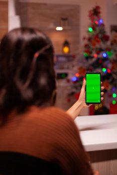Young woman holding smartphone with green screen for virtual technology on mockup template. Caucasian person analyzing digital device with chroma key to view background design concept