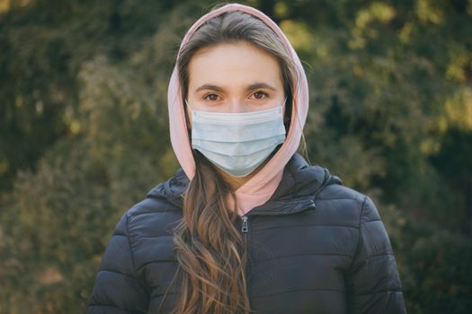 Attractive Girl Takes on Medical Mask. Breathes deeply and looking at camera on green background. Health care and medical concept.