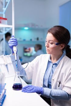 Scientist looking into micropipette for biology test . Woman research a new experiment in modern lab, analyzing pharmaceutical work with modern equipment.
