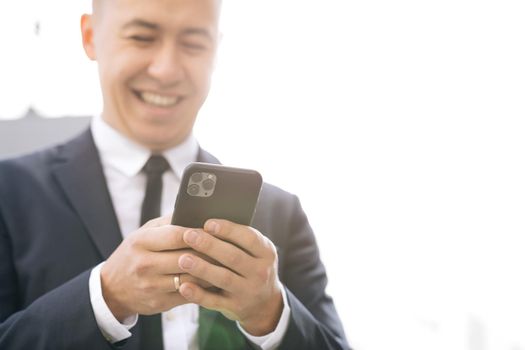 Stylish Businessman Exiting from the Modern Office. Using his Smartphone. Sliding on Mobiles Screen. Looking Successful, Confident on Summer Day.