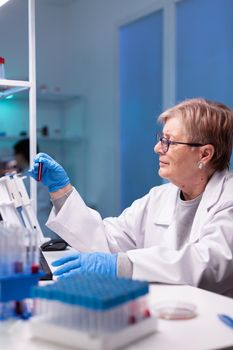 Professional chemist taking a sample for medical expertise. Professional researcher working in modern laboratory with blood tube to discovery vaccine against coronavirus