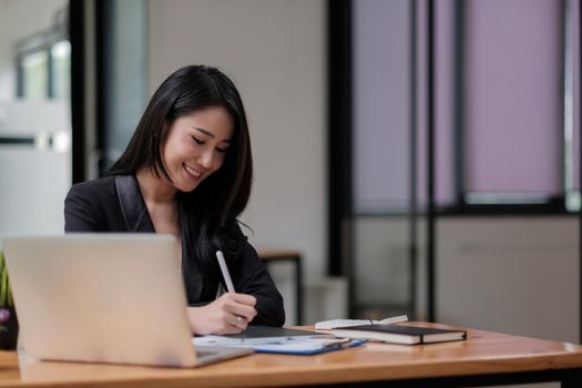 Asian woman hand with pen stylus while using digital tablet for financial analysis.