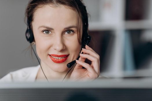 Attractive young female customer service agent talking to a customer with a telephony headset as she looks at the camera.
