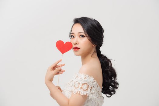 Attractive young Asian woman holding love sign when standing over white background.