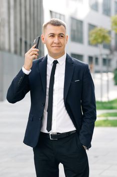 Portrait handsome man having phone talk outdoor. Business man talking on smartphone at street. Happy man call phone outdoor. Office employee talking mobile phone outside.
