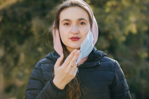 Girl Takes Off Medical Mask During Coronavirus COVID-19 Epidemic. Breathes deeply and smiling looking at camera. Health care and medical concept