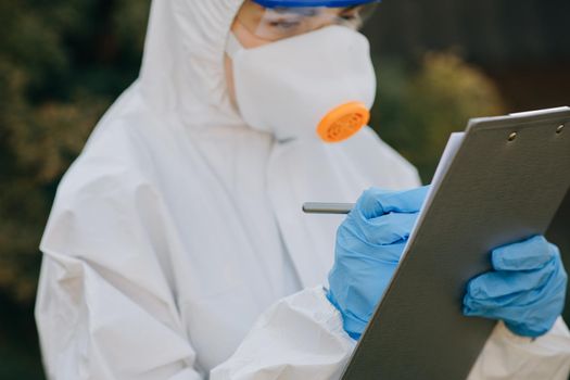 Doctor epidemiologist fighting with coronavirus COVID-19. The Virologist hand in a white glove holds a pen on a blank sheet of paper.