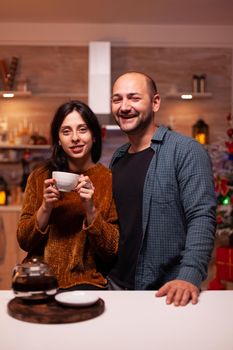 Portrait of happy family looking into camera while celebrating christmas winter holiday standing in xmas decorated kitchen. Cheerful joyful enjoying spending wintertime together. Christmastime