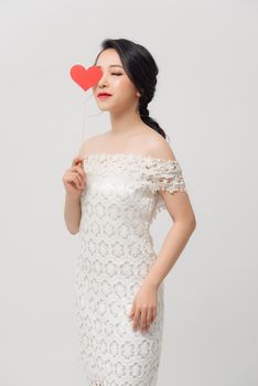 Elegant Asian woman holding a parper heart and standing isolated over white background.