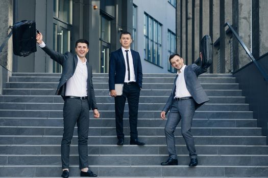 Three business people standing on stairs. Confident businessmen with leather briefcase.