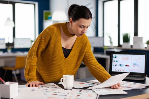 Project leader preparing presenstation for investors using printed charts. Executive entrepreneur, manager leader standing working on documents projects.