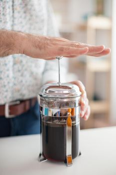 Close up of old man making coffee with a french press. Elderly person in the morning enjoying fresh brown cafe espresso cup caffeine from vintage mug, filter relax refreshment