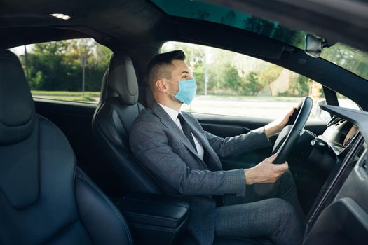 Pandemic. Citizens. Lockdown safety. Adult businessman wearing medical mask in prevention for coronavirus and driving his car to work. Businessman healthcare.