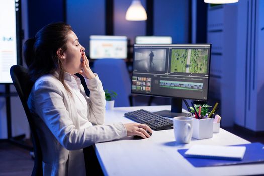 Creative content creator working at postproduction montage to respect deadline sitting at desk in start-up business office. Woman videographer editing audio film on professional laptop at midnight.