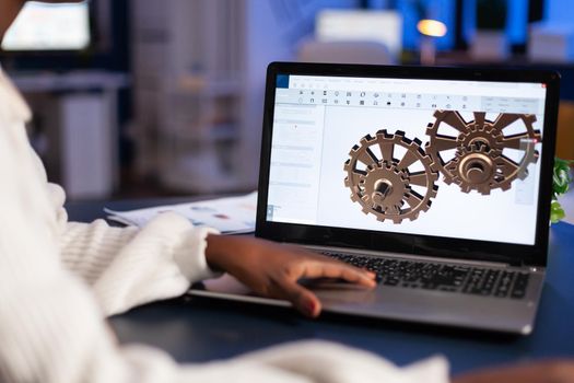 Close up of mechanical gears while engineer working with software for mechanism design. Freelancer studying prototype idea on pc showing cad software on device display.