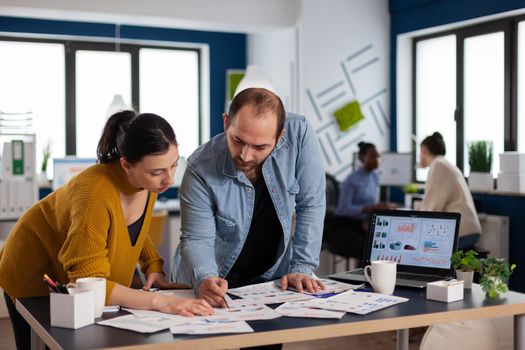 Multi ethnic coworkers team of start up consulting about marketing strategy. Diverse team of business people analyzing company financial reports from computer.