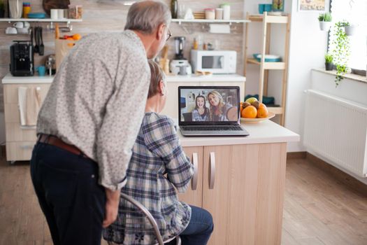 Senior retired couple talking with niece via internet video call. Online call with daughter and niece. Elderly person using modern communication online internet web techonolgy.