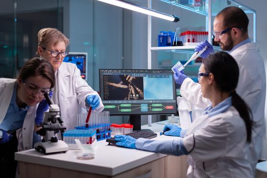 Team of scientific investigation examining resultes of DNA test in equipped lab. Biochemist scientists conducting treatment research trying to discover vaccine against covid19 virus using blood test