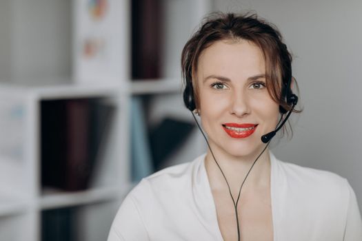 Attractive young female customer service agent talking to a customer with a telephony headset as she looks at the camera.