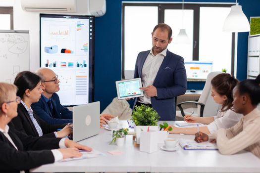 Company leadership explaining briefing project in conference room to team. Project leader discussing with teamworkers in broadroom, analysing charts, graphs, financial evolution of company.