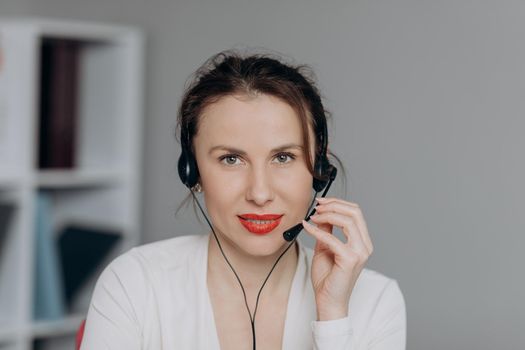 Young Beautiful Woman Operator with Phone Headset Looking at Camera and Smiling. Young Smile Operator Working with a Headset and Happy Smile Face to the Camera