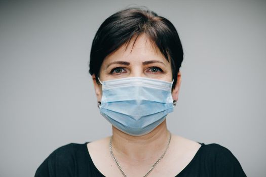 Woman Wearing Medical Mask During Coronavirus COVID-19 Epidemic. Sick woman wearing protection during pandemic. Pretty Caucasian Woman Taking on Medical Mask.