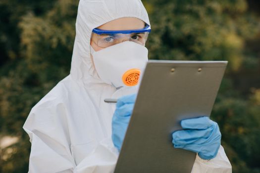 Doctor epidemiologist fighting with coronavirus COVID-19. The Virologist hand in a white glove holds a pen on a blank sheet of paper.