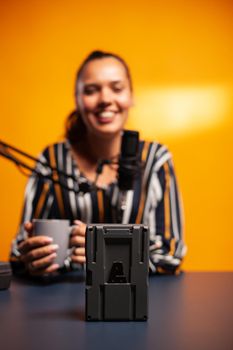 Videographer filming battery with v-lock during podcast. Professional videography gear review by content creator new media star influencer on social media.