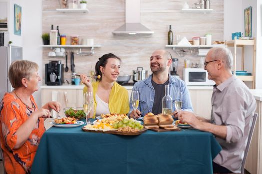 Woman laughing at lunch with her family and roasted potato. Cheerful senior parents with older kids smiling.