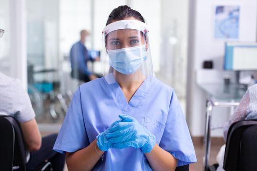 Medical physician wearing face mask against coronavirus looking at camera in hospital waiting area. Doctor consulting senior man in examination room. Physician, epidemic, care, surgical, corridor.