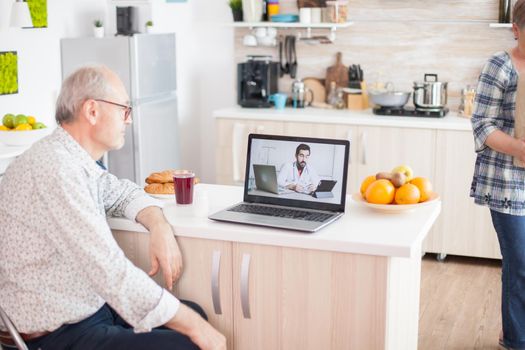 video conference with doctor using laptop in kitchen. Online health consultation for elderly people drugs ilness advice on symptoms, physician telemedicine webcam. Medical care internet chat