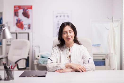 Portrait of successful woman doctor in hospital office wearing white coat looking at the camera. Happy specialist medic.