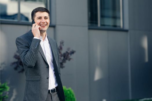 Portrait of Confident Businessman in Classical Suit Talking on Smartphone and Walking in Street. Young Business Man Having Business Conversation