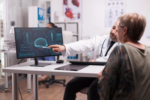 Young radiologist with senior patient in hospital office explaining brain ct scan after accident. Medic wearing white coat and stethoscope.