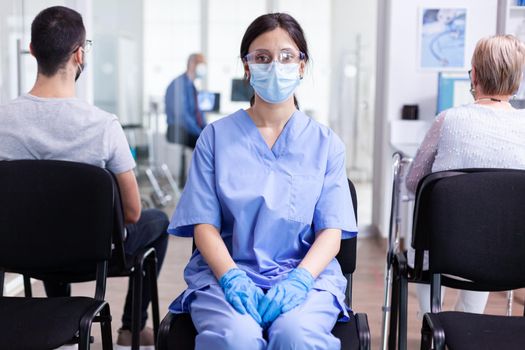 Female nurse with face mask against coronavirus in hospital waiting area. Doctor consulting senior man in examination room. Physician, epidemic, care, surgical, corridor.