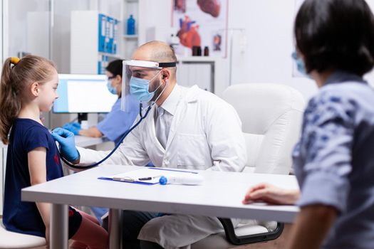 Doctor examining girl by stethoscope. Health pediatrician specialist providing health care services consultations treatment in protective equipment for consultation.