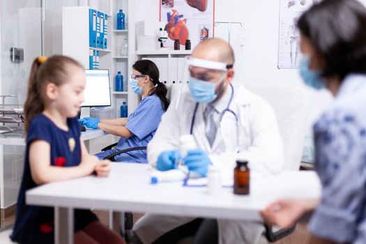 Nurse with face mask against coronavirus in hospital office. Health pediatrician specialist providing health care services consultations treatment in protective equipment for consultation