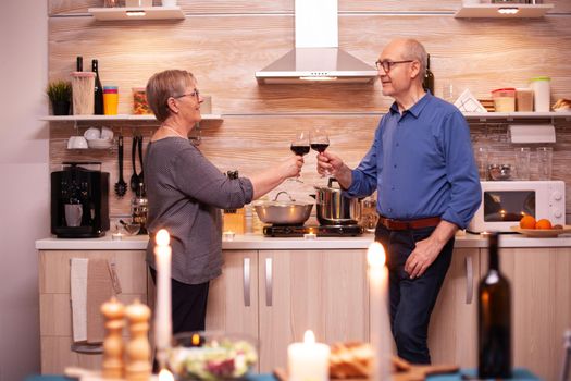 Husband and wife discussing about their relationship while toasting glasses with red wine. Aged couple in love talking having pleasant conversation during healthy meal.
