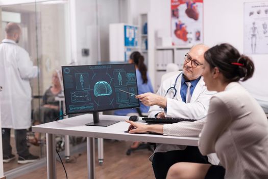 Mature doctor explaning x-ray for young woman patient in hospital office and the treatment for brain injury. Young medic in white coat talking about illness diagnosis with disabled senior woman in wheelchair.