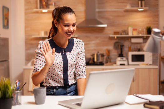 Woman smiling and saying hello during video confernce while working from home. Employee using modern technology at midnight doing overtime for job, business, career, network, lifestyle ,wireless.