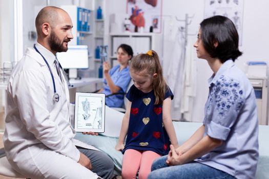 Doctor holding tablet pc with digital radiography during consultation of child. Healthcare physician specialist in medicine providing health care services treatment examination.