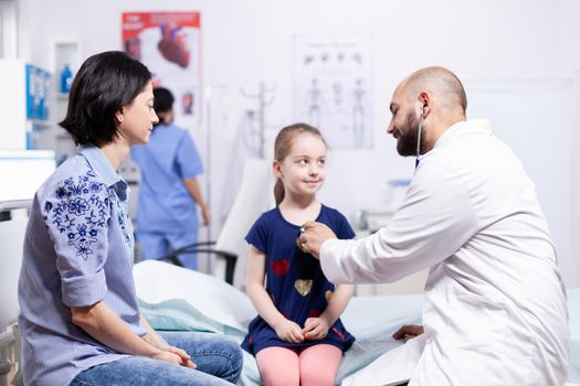 Pediatrician checking health of child using stethoscope in hospital office during consultation. Healthcare physician specialist in medicine providing health care services treatment examination.