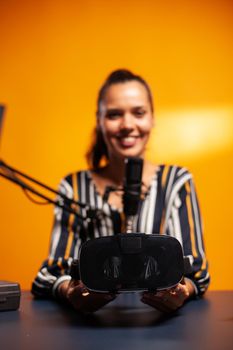 Woman presenting vr headset for games in podcast. Video blog studio review of weareble technology with stereoscopic cyber reality, electronics gadget experience, gaming industry