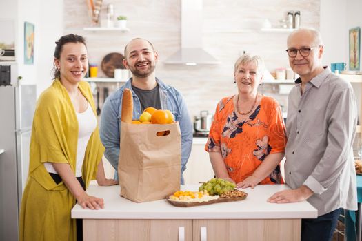 Multi generation family smiling looking at camera in kitchen.