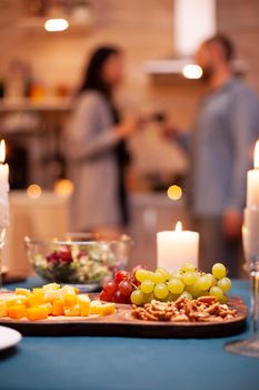 Candle burning on table and close up of grapes on wooden table in kitchen while couple toasting.