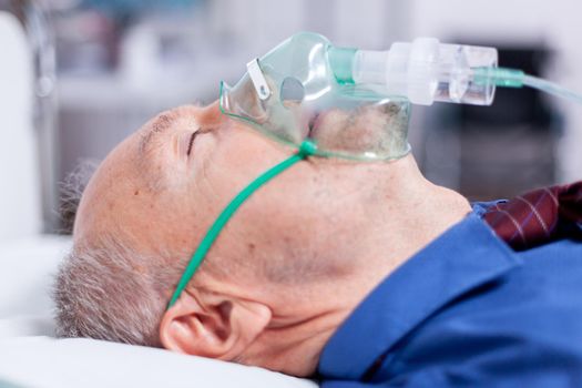 Sick old man with respiratory mask laying on hospital bed after being infected with coronavirus. Medicine medical healthcare system epidemic lungs infection treatment